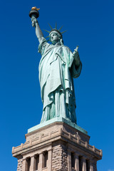 Fototapeta premium Statua Wolności i cokół na jasnym, granatowym niebie w słoneczny dzień