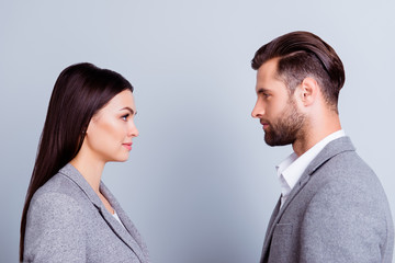 Concept of confrontation in business. Close up photo of two young serious confident people standing...