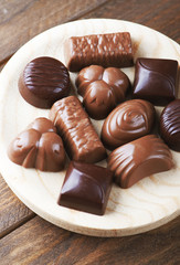 From above candy assortment placed in a wooden bowl. Vertical studio shot.