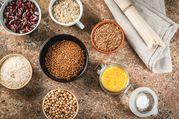 Selection of gluten-free products, cereals: xanthan gum. buckwheat,Rice, rice noodles, chickpeas, lentils, corn, beans, oatmeal. In bowls and jars, the top view on stone table top view copy space