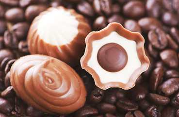 Close-up shot of chocolates of various flavors and shapes on coffee beans placed on the canvas.