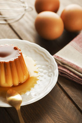 Verticall studio shot of sweet flan dessert and eggs on the wooden table.