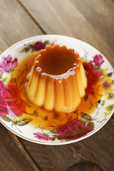 Verticall studio shot of sweet flan dessert on a colorful plate.