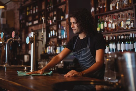 Young waiter cleaning a counter