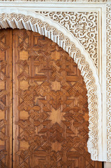 Detail of wood carving and stone sculpture. Large arabic style door in precious wood. Alhambra, Granada, Spain