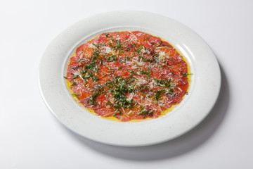 Beef carpaccio served with ruccola on a white plate