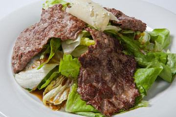 Beef salad with lettuce and cheese on a white plate