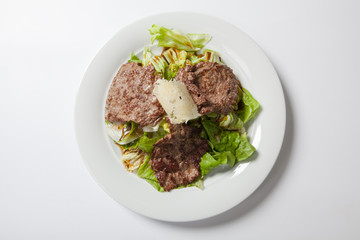 Beef salad with lettuce and cheese on a white plate