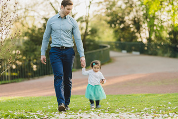 Fototapeta premium toddler girl in park with father on background