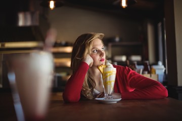 Thoughtful woman having milkshake