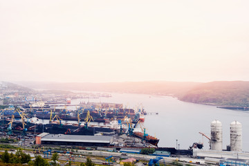 Embankment along with the river port, the crane unloads the coal from the box and loads it into the truck. Murmansk, Russia.Concept logistics, transportation, transport.