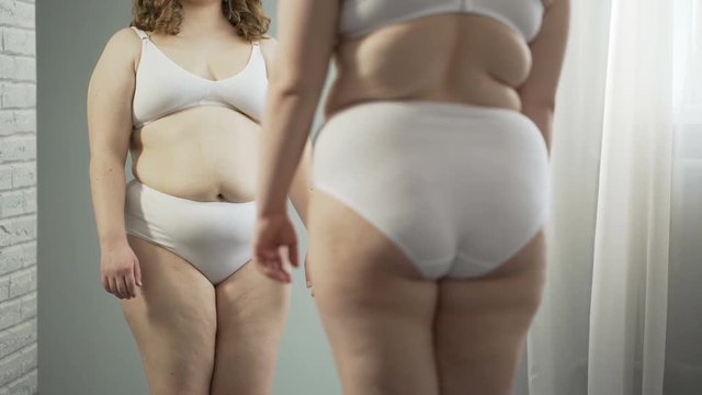 Obese woman getting on scales for weight control during healthy diet, weightloss