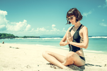 Young healthy attractive woman practicing yoga on the beach Nusa Dua, tropical Bali island,...
