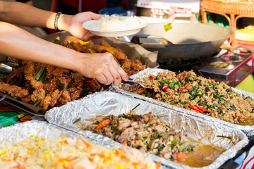 seller with rice and wok food at street market