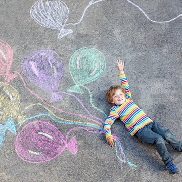 Kid boy having fun with colorful balloons drawing with chalks