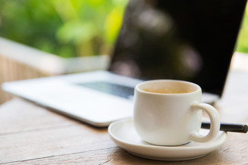 close up of coffee cup and laptop on table