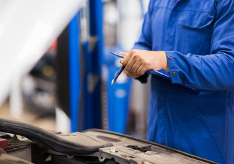 auto mechanic man with clipboard at car workshop