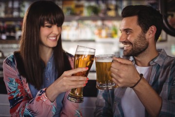 Happy couple toasting glasses of beer at counter