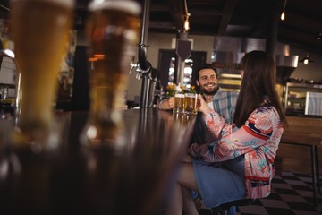 Happy couple interacting while having beer at counter