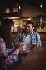 Couple interacting while having beer at counter