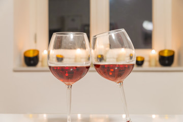 Zwei Gläser mit Rotwein auf einem weißen Tisch vor weißem Hintergrund und Fenster