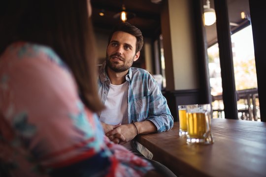 Couple interacting while having beer at counter