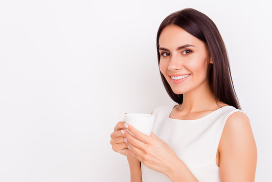 Close up portrait of young successful businesslady on a coffee break, she is resting and enjoying the drink. Woman is on a white background, she is smiling