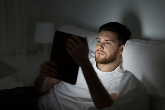 young man with tablet pc in bed at home bedroom