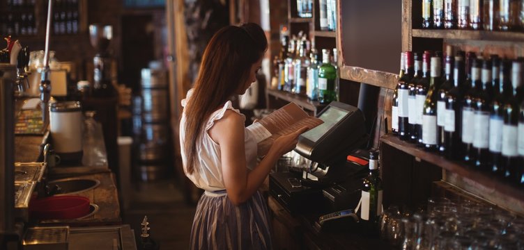 Female bar tender looking at menu