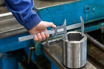 Close-up of the hand of a worker measuring a part from the mechanism of an accurate measuring instrument