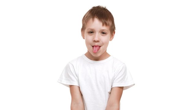 Embarassed elementary-school aged boy standing on white background smiling and showing tongue