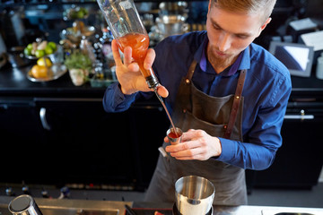 barman pouring alcohol to cocktail jigger at bar