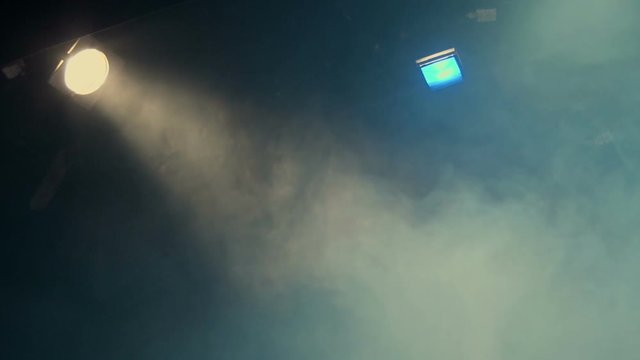 Theatrical smoke. The rays of light from the floodlights at the theater during the performance. Gradual turning off of the light source with dimmer switch. Lighting equipment