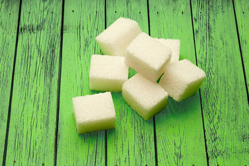 Sugar cubes on green wooden background