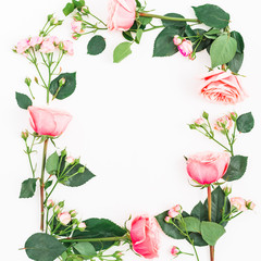 Flat lay floral frame made of pink roses, leaves and buds on white background. Top view.