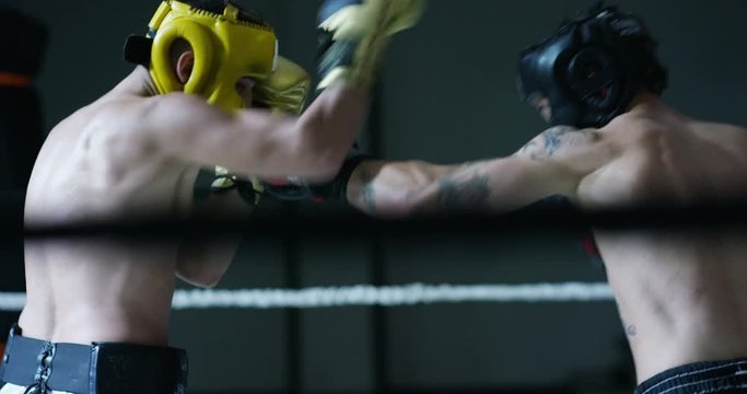 Professional sparring of two (young) partners of boxers in the ring, practice strike technique, rack, defense and endurance, in protective helmets. Concept: love sports, young boxers, love to win.