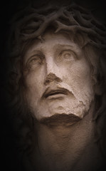 Face of Jesus Christ crown of thorns against dark background (statue)