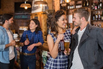 Happy friends holding beer glass and bottle in pub