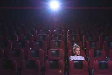 Fototapeta na wymiar Blonde girl watching movie in empty theater