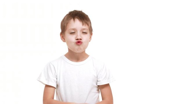 Elementary-school aged Caucasian boy making faces and kidding around standing on white background