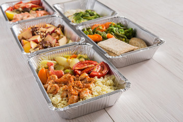 Healthy food take away in foil boxes on wood background