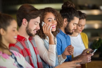 Woman talking on smartphone while friends using mobile phone