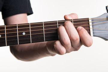 Fototapeta premium The guitarist's hand clamps the chord E on the guitar, on a white background. Horizontal frame