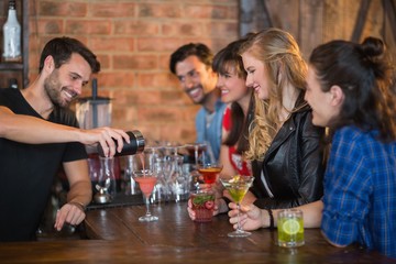 Smiling bartender serving drink for customers