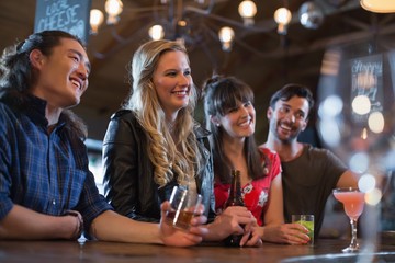Smiling friends counter looking away in pub
