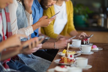 Group of friends using mobile phone while sitting at table