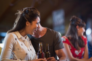 Cheerful woman looking away while holding beer bottle