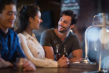 Smiling friends interacting at bar counter