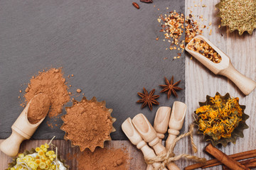Different spices in bakeware with wooden scoops on the slate slone background