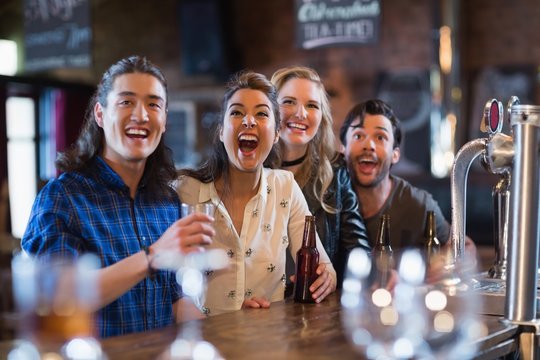 Cheerful friends standing by bar counter